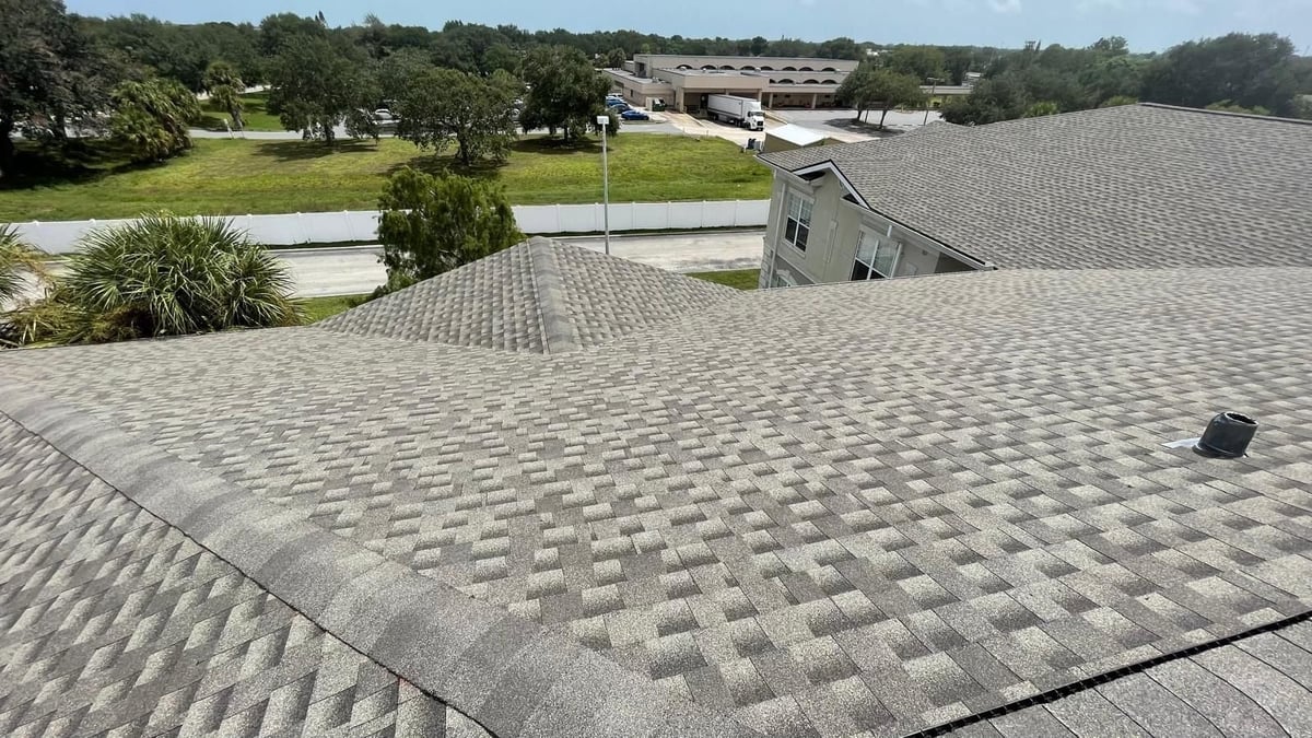 Close-up of new architectural shingles with hip ridge caps and a roof vent on a commercial care facility